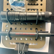 A car visor organizer with black tactical flashlight and a black cylindrical rod with red 'RED CLOVER GEAR' branding, displayed.