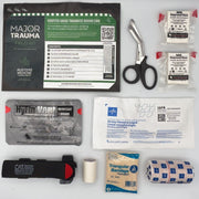 Collection of medical supplies including a trauma kit, scissors, bandages, and a flashlight on a white background.